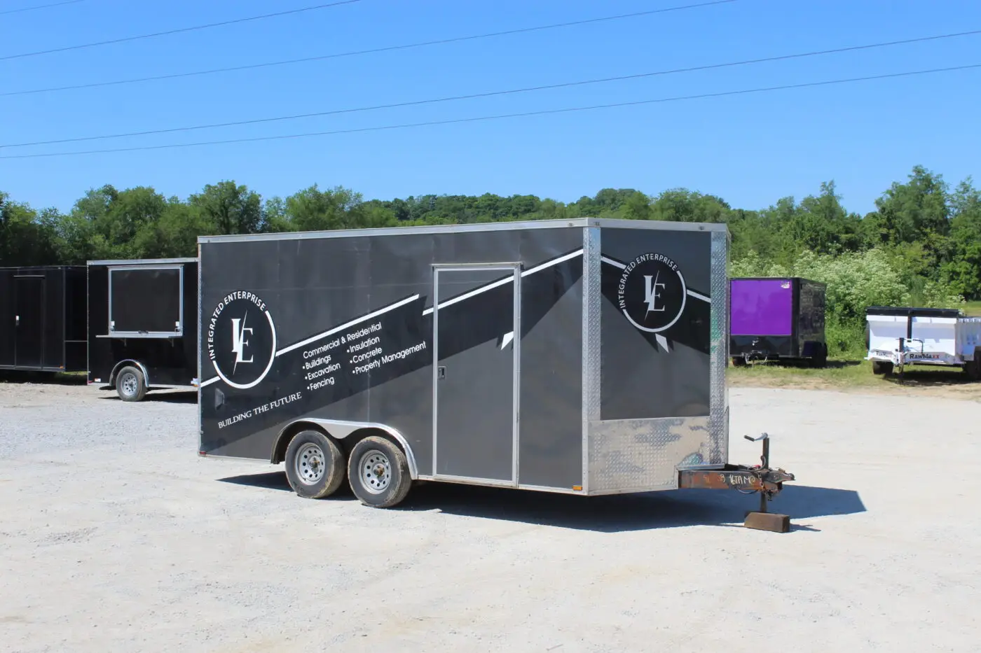 Black enclosed construction trailer parked on gravel lot