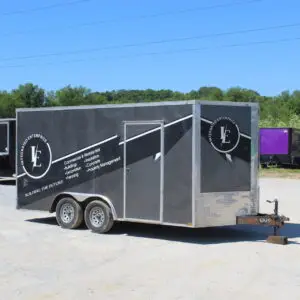 Black enclosed construction trailer parked on gravel lot