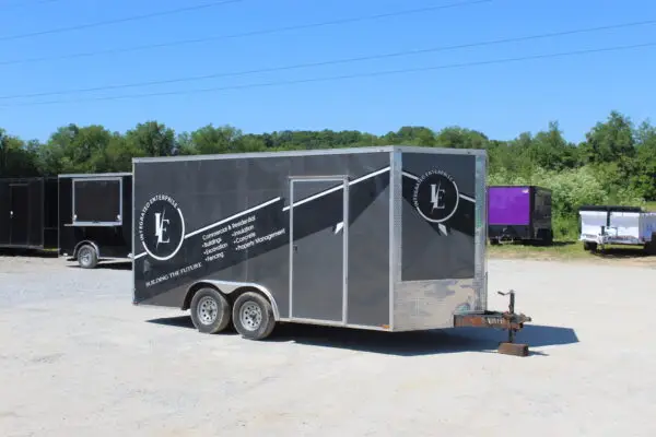 Black enclosed construction trailer parked on gravel lot