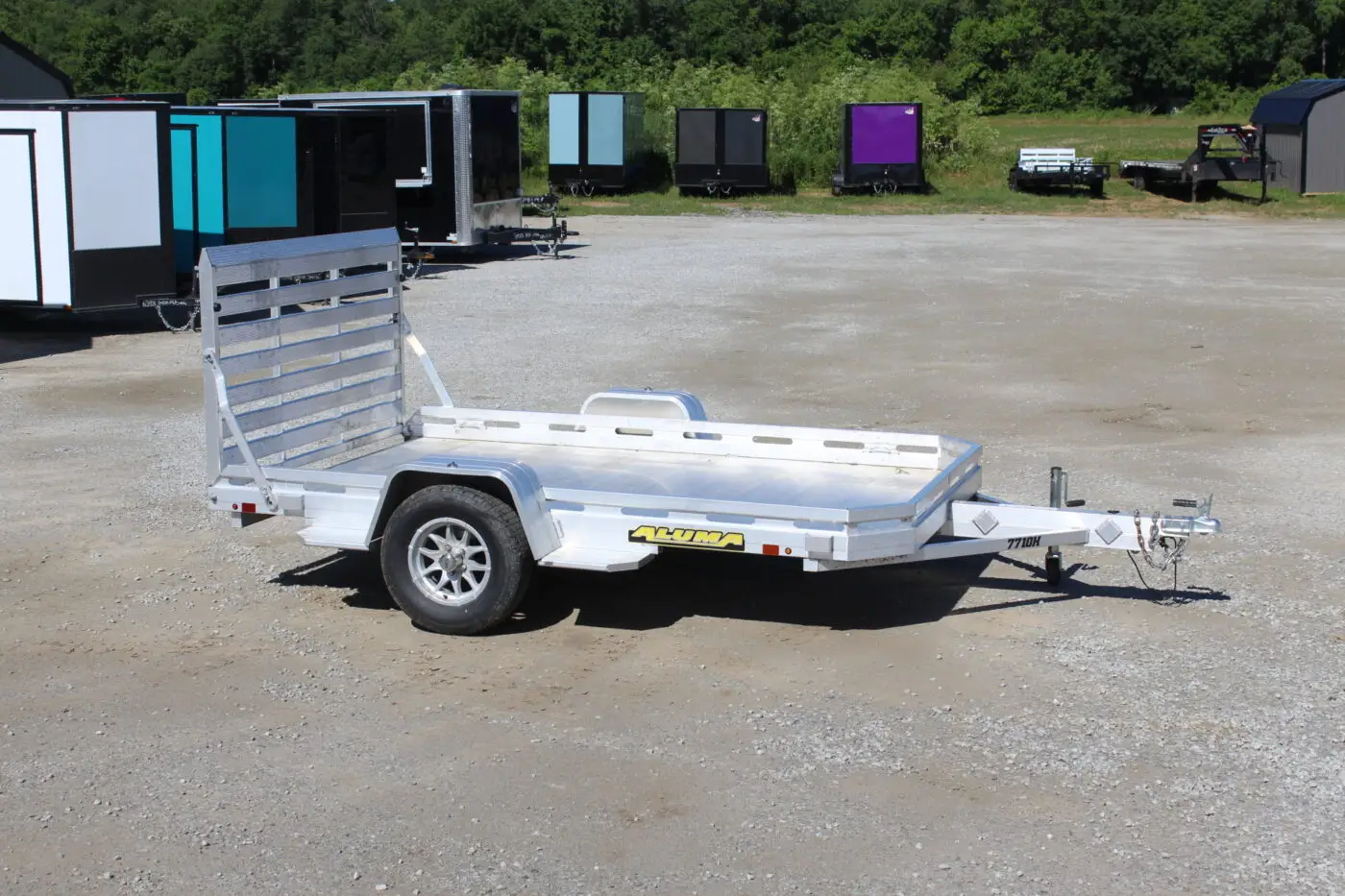 Aluminum utility trailer parked on gravel lot