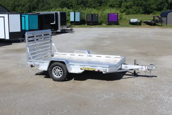 Aluminum utility trailer parked on gravel lot