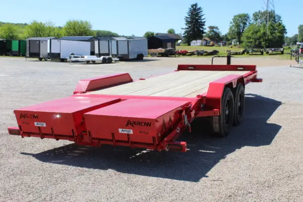 Red flatbed equipment trailer on gravel lot