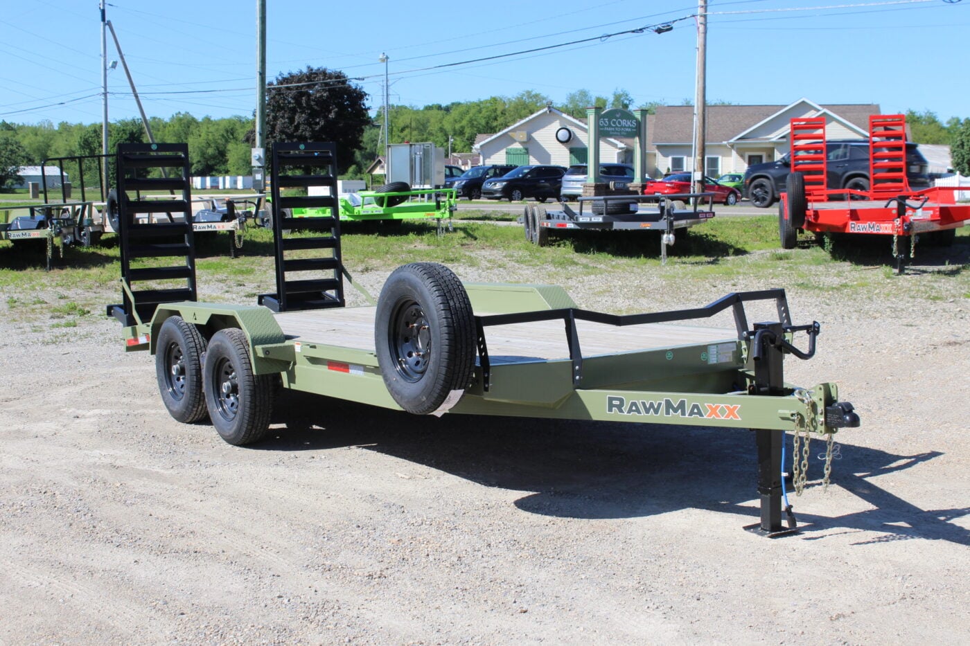 Green dual-axle equipment trailer on gravel lot