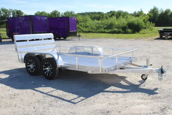 Aluminum dual-axle utility trailer on gravel lot
