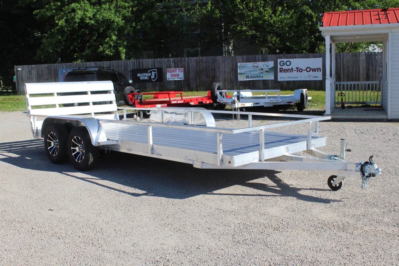 Aluminum dual-axle utility trailer on gravel lot
