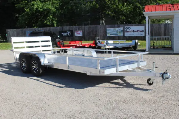 Aluminum dual-axle utility trailer on gravel lot