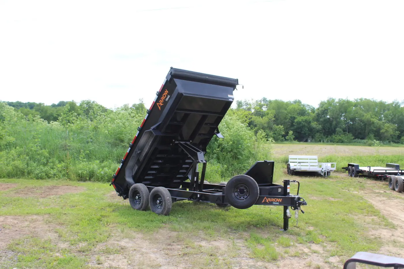 Black dump trailer with raised bed in field