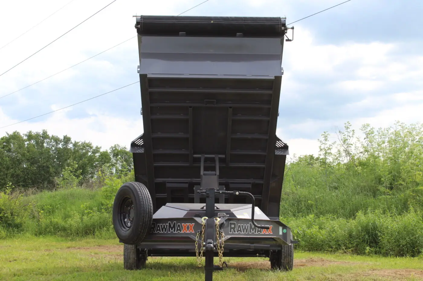 Raised black dump trailer in grassy field