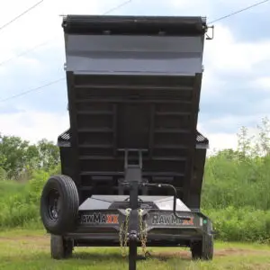Raised black dump trailer in grassy field