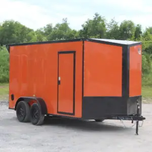 Orange enclosed cargo trailer parked on gravel lot