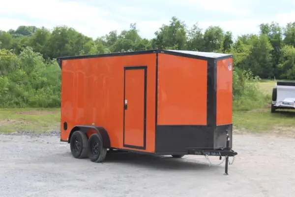 Orange enclosed cargo trailer parked on gravel lot