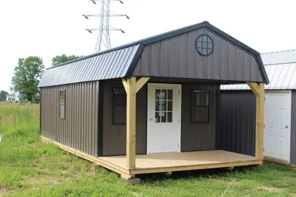 Small metal cabin with porch in grassy field
