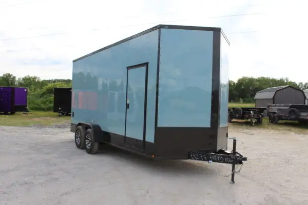 Light blue enclosed cargo trailer on gravel lot