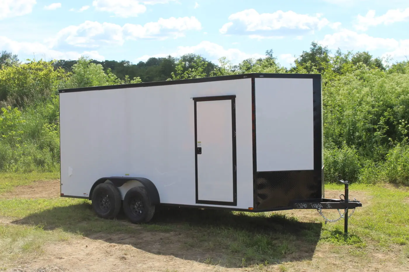 White enclosed cargo trailer parked on grass